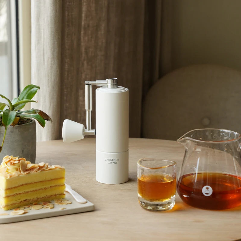 Moulin à café manuel blanc sur une table avec une carafe de café